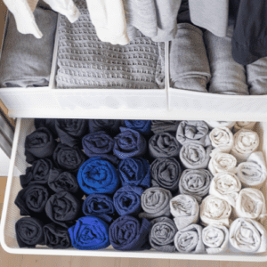 neatly rolled t-shirts and folded sweaters in a organized closet